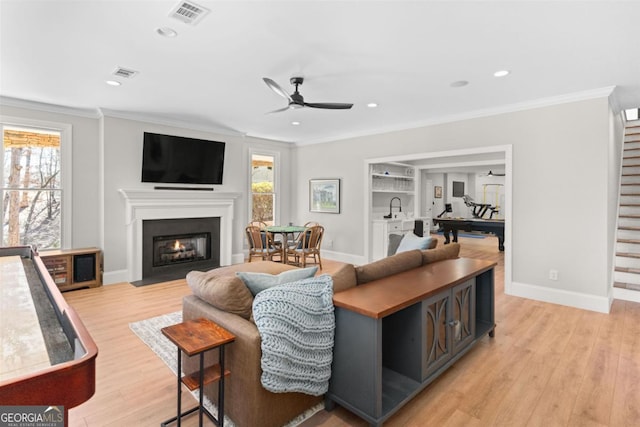 living area with plenty of natural light, visible vents, and crown molding