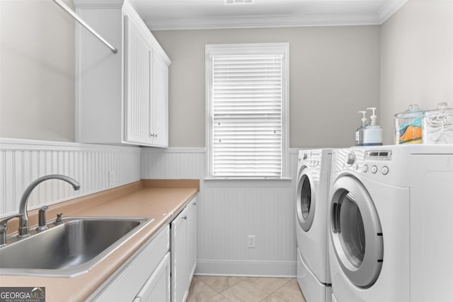 laundry room featuring a wainscoted wall, crown molding, cabinet space, washing machine and dryer, and a sink