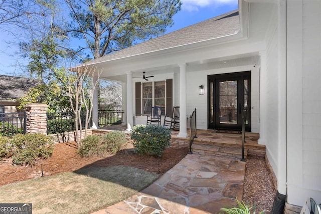 entrance to property with covered porch, ceiling fan, fence, and a shingled roof