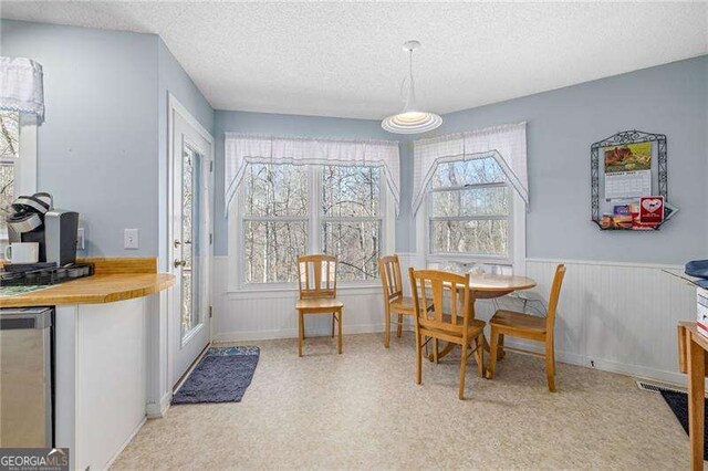 dining space with lofted ceiling, a textured ceiling, a notable chandelier, and light colored carpet