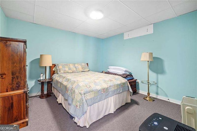 carpeted bedroom with a paneled ceiling and baseboards