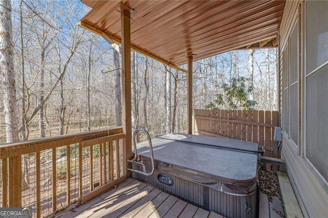 wooden terrace featuring a covered hot tub and fence