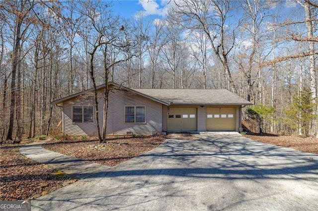 exterior space featuring a garage, a forest view, and driveway