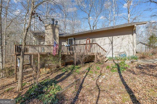 back of property with a chimney and a wooden deck