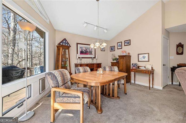 dining room featuring light carpet, an inviting chandelier, vaulted ceiling, and track lighting