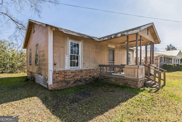 view of side of home with brick siding, a lawn, and fence