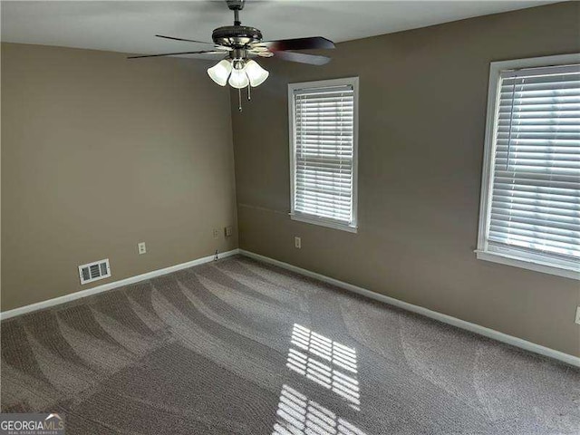 carpeted spare room featuring a ceiling fan, visible vents, and baseboards