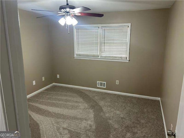 empty room with carpet floors, a ceiling fan, visible vents, and baseboards