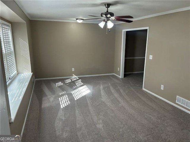 carpeted spare room with ornamental molding, visible vents, and baseboards