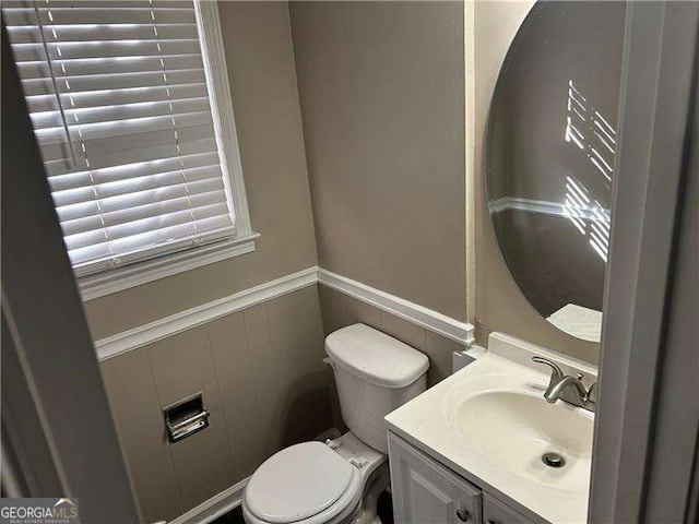 half bath with toilet, wainscoting, and vanity