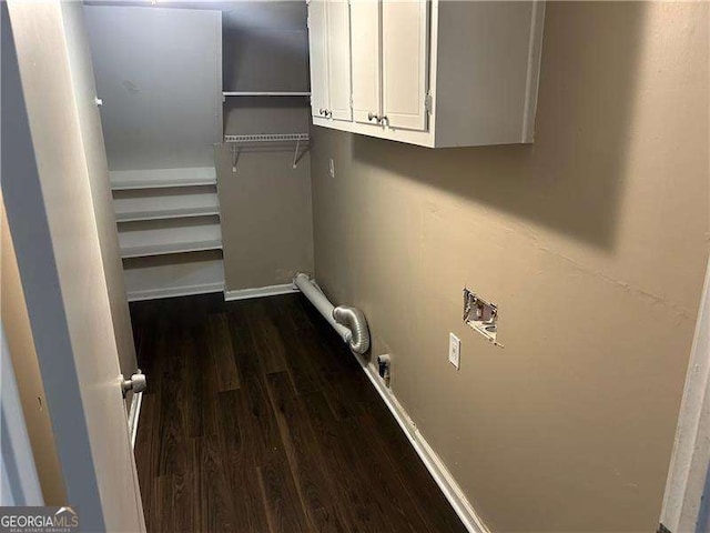 washroom featuring dark wood-type flooring, washer hookup, and cabinet space