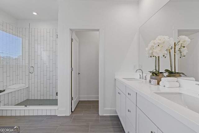 full bath featuring double vanity, a stall shower, a sink, and baseboards