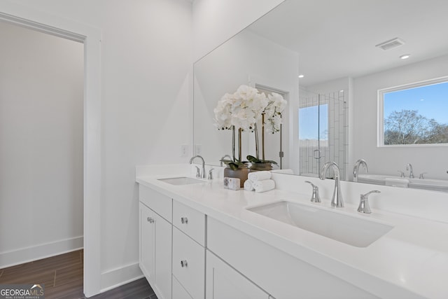 full bathroom with wood finished floors, a sink, visible vents, and a shower stall