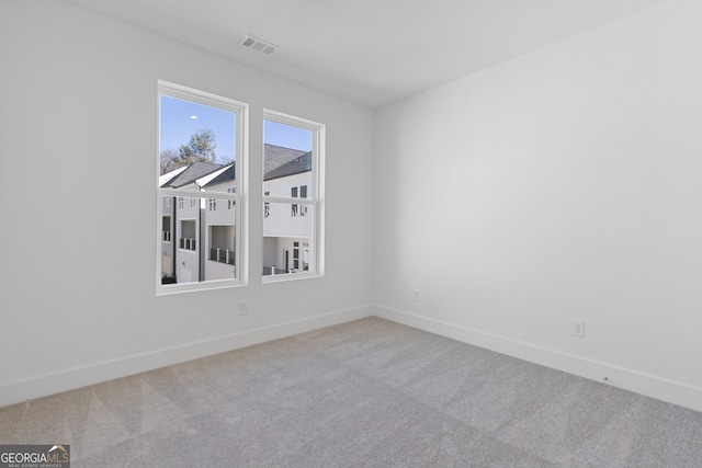 carpeted spare room featuring visible vents and baseboards