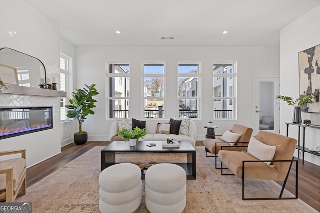 living room with recessed lighting, visible vents, wood finished floors, and a glass covered fireplace