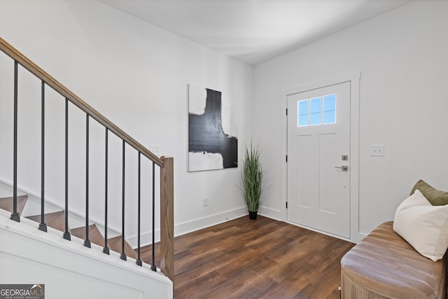 foyer entrance featuring stairs, dark wood-type flooring, and baseboards