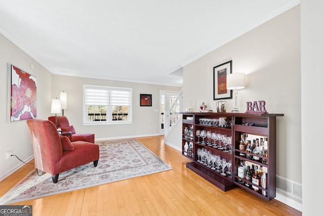 living area featuring baseboards, wood-type flooring, and crown molding