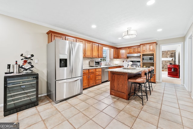 kitchen with beverage cooler, stainless steel appliances, a sink, a kitchen breakfast bar, and backsplash