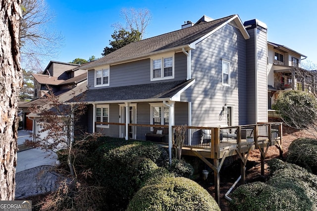 view of front facade featuring a porch, roof with shingles, and a chimney