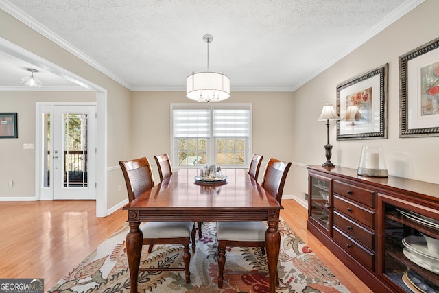 dining space featuring a textured ceiling, light wood-type flooring, and a healthy amount of sunlight