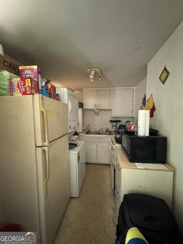 kitchen featuring light floors, light countertops, freestanding refrigerator, white cabinetry, and black microwave