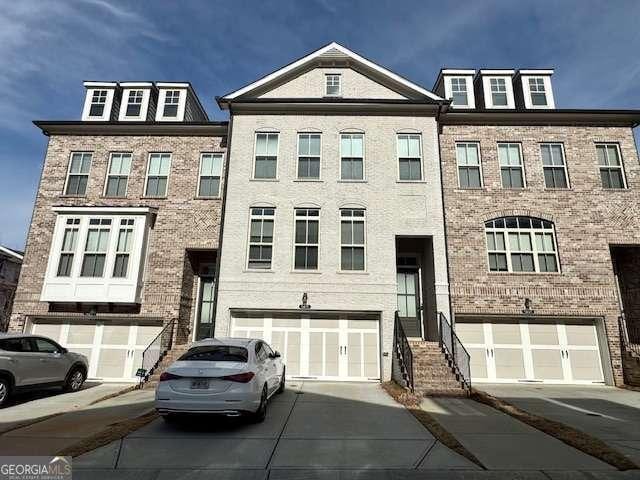 multi unit property featuring brick siding, driveway, and an attached garage