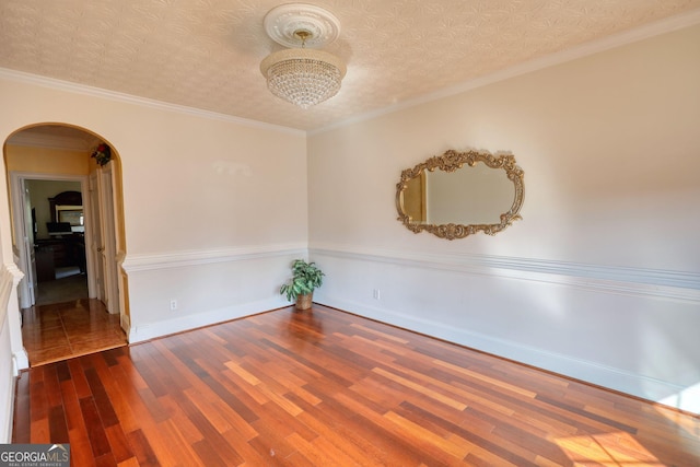 unfurnished room with arched walkways, ornamental molding, dark wood finished floors, and baseboards