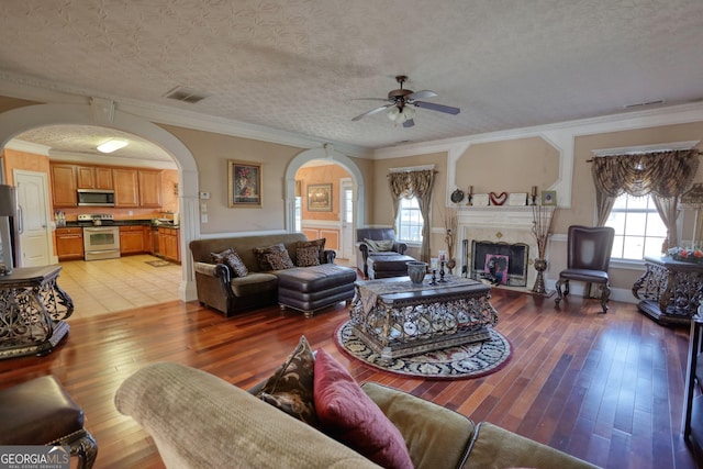 living room with light wood finished floors, a fireplace, visible vents, and a textured ceiling