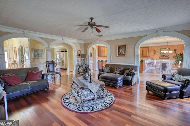 living area featuring arched walkways, a textured ceiling, and wood finished floors