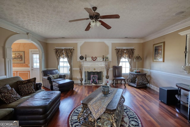 living room featuring a textured ceiling, a fireplace with flush hearth, dark wood finished floors, and crown molding