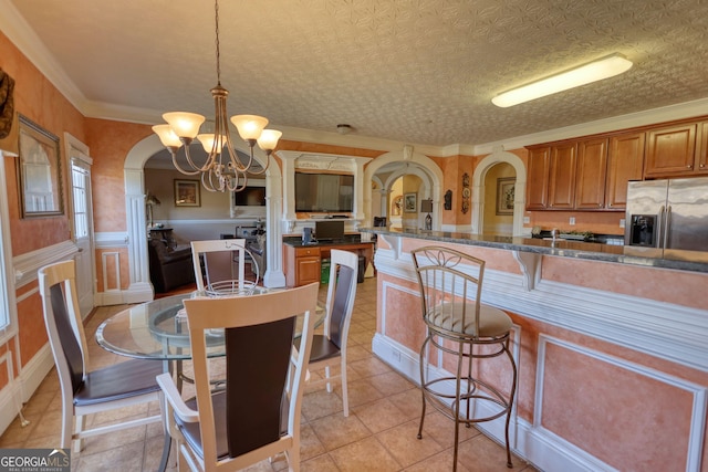 dining room with arched walkways, light tile patterned floors, a notable chandelier, wainscoting, and crown molding