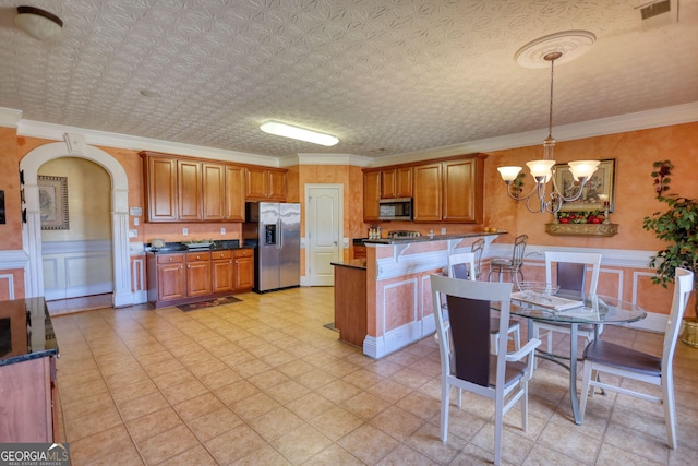 kitchen featuring arched walkways, brown cabinets, decorative light fixtures, dark countertops, and appliances with stainless steel finishes