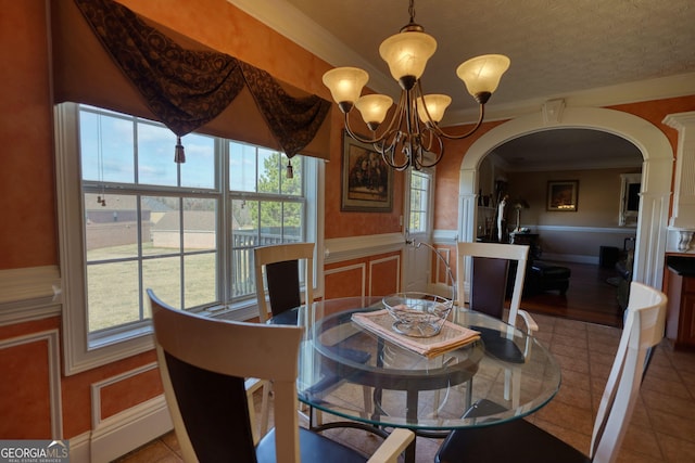 dining space with a chandelier, wainscoting, a decorative wall, and light tile patterned floors