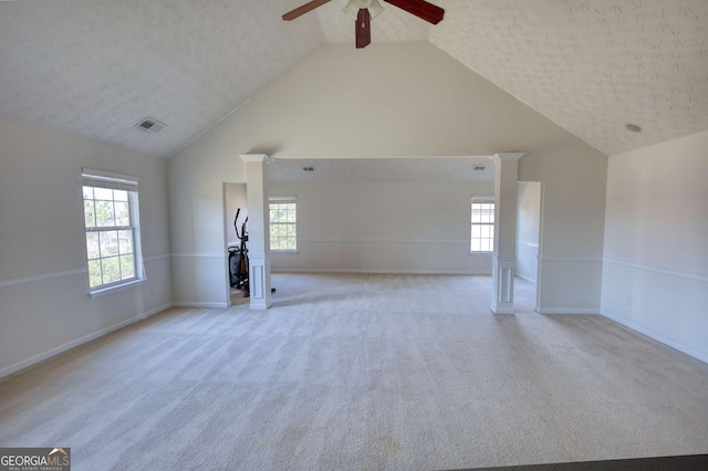 empty room featuring high vaulted ceiling, a wealth of natural light, visible vents, and light colored carpet