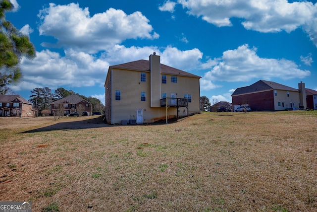 rear view of house featuring a residential view, a lawn, and a chimney