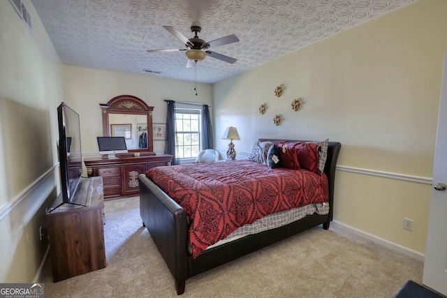 bedroom featuring baseboards, visible vents, light colored carpet, ceiling fan, and a textured ceiling