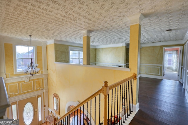 hall featuring an ornate ceiling, dark wood-type flooring, ornamental molding, and an upstairs landing