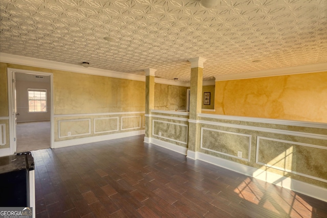 empty room featuring ornamental molding, wainscoting, decorative columns, and an ornate ceiling