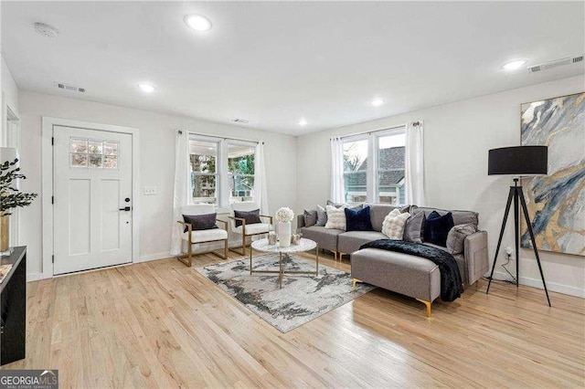 living area with a wealth of natural light, light wood-type flooring, and visible vents