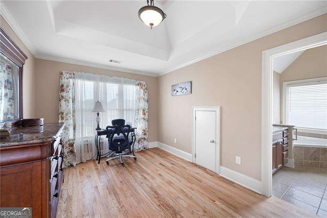 office area featuring a tray ceiling, crown molding, visible vents, light wood-type flooring, and baseboards