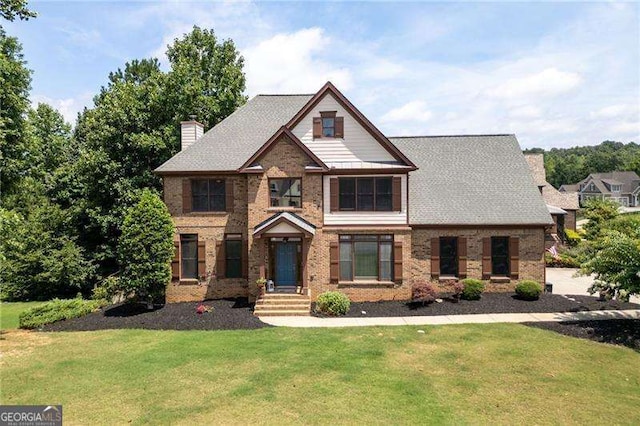 view of front of property with brick siding, a chimney, and a front lawn