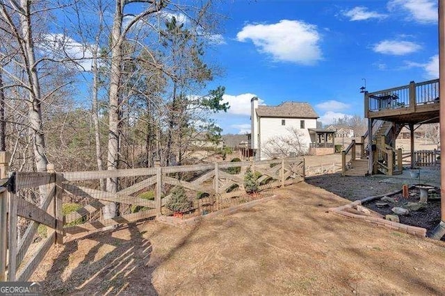 view of yard featuring fence, a wooden deck, and stairs