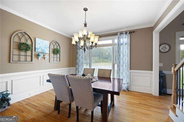 dining room featuring wainscoting, light wood-style flooring, stairway, crown molding, and a notable chandelier