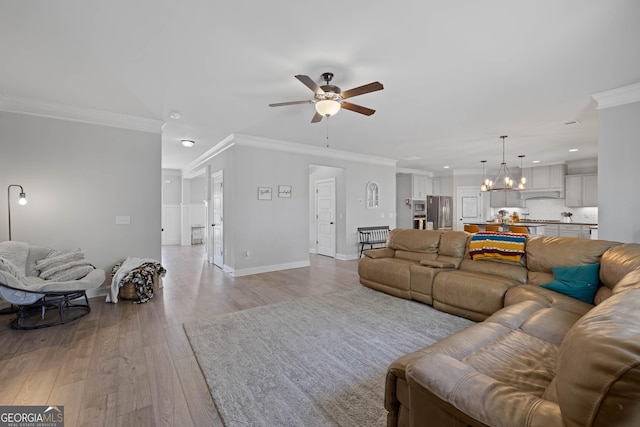 living room with crown molding, recessed lighting, light wood-style floors, baseboards, and ceiling fan with notable chandelier