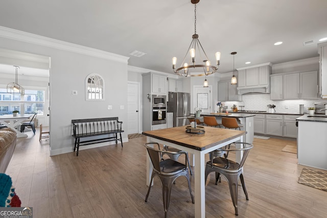 dining space with crown molding, recessed lighting, an inviting chandelier, light wood-style floors, and baseboards