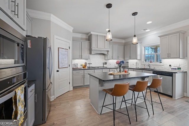 kitchen with stainless steel appliances, dark countertops, a center island, and gray cabinetry