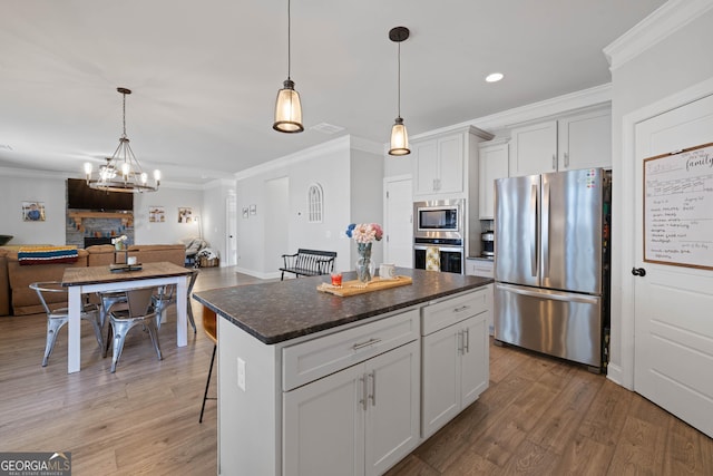 kitchen with dark countertops, appliances with stainless steel finishes, open floor plan, a center island, and pendant lighting