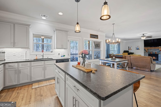 kitchen with a fireplace, visible vents, open floor plan, a center island, and dark countertops