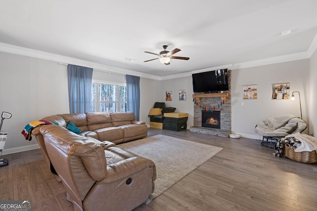 living area featuring a fireplace, crown molding, baseboards, and wood finished floors