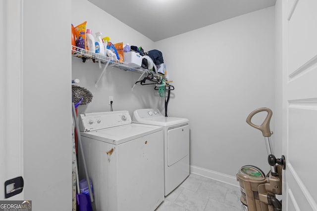 washroom featuring laundry area, baseboards, and washer and dryer